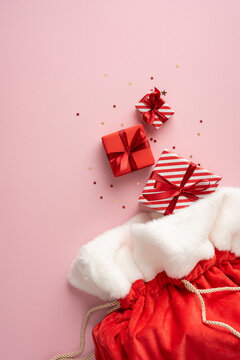 Merry Christmas and happy New Year: Santa Claus presents in a red velvet sack with wrapped gifts on vertical pastel pink backdrop