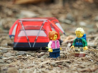 Naklejka premium Indonesia - May 9, 2023 : Mini toy of action figure at grassland with blurred background. Toy photography concept. Camping with tent at outdoor conceptual design. Man and Woman character.