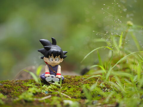 Indonesia - February 14, 2023 : Son Goku character at green land. Blurred view of grass at land. Background is blurred and bokeh.