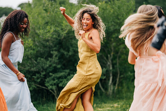 Joyful women dancing and laughing together outside