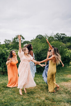 Joyful women in colorful dresses dancing outdoors