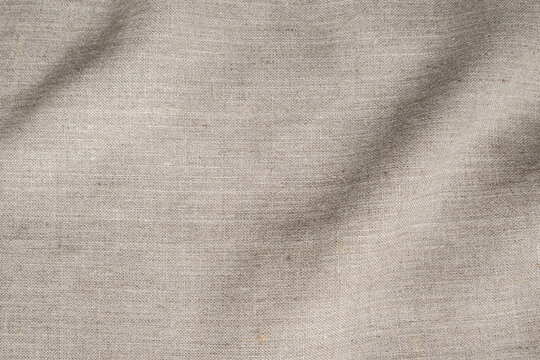 Natural beige linen fabric texture background with soft waves, beautiful cloth pattern surface for design overlay and backdrop material.