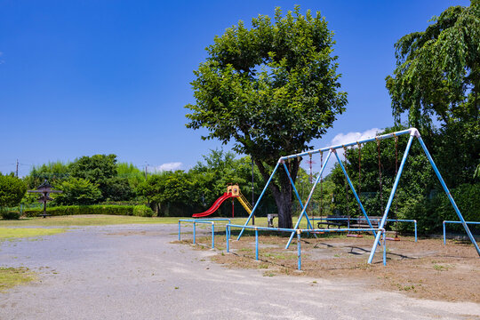 晴天の公園に設置されたブランコと滑り台と青空（横構図）