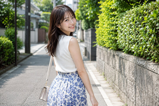 緑の住宅街を振り返って歩く女性の夏ポートレート
