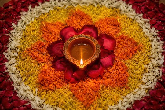 Traditional clay diya burning amid colorful flower petals during a Diwali celebration