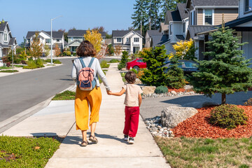 Mother and son walking hand in hand through suburban neighborhood