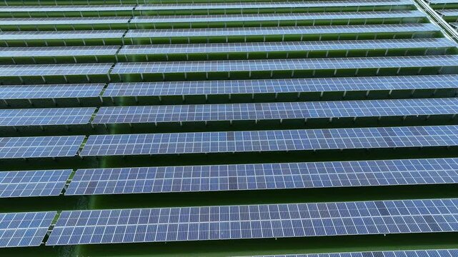 Aerial view of a large solar panel farm with organized photovoltaic arrays, representing renewable energy generation, clean technology, and sustainable power solutions for a greener future.

