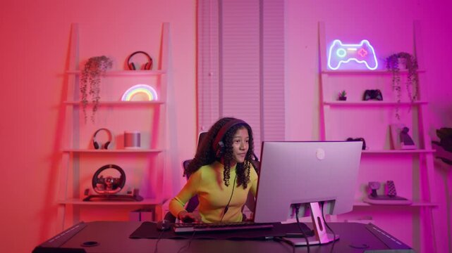 African American teenage girl playing online video game on computer. 