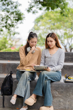 Two Young Asian Female College Students Studying Together with Laptop Outdoors on Campus Steps