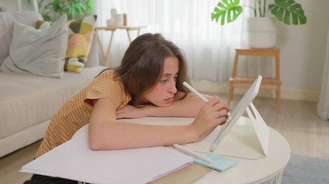 Tired Caucasian woman using a digital tablet while working from home. 