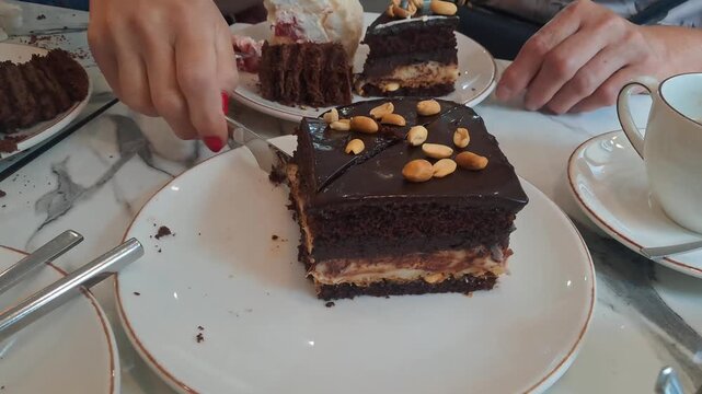 a person cutting a slice of chocolate cake on a marble table with a knife and fork