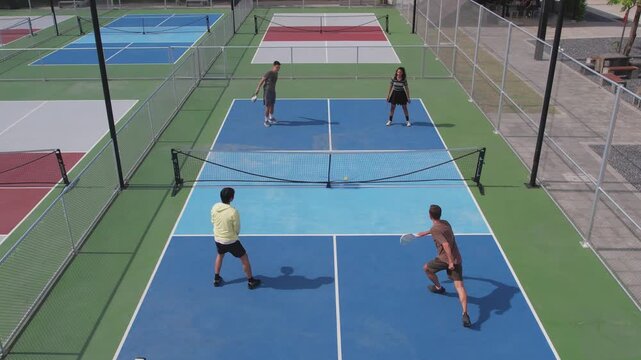 Aerial view of young man and woman playing pickleball on outdoor court.