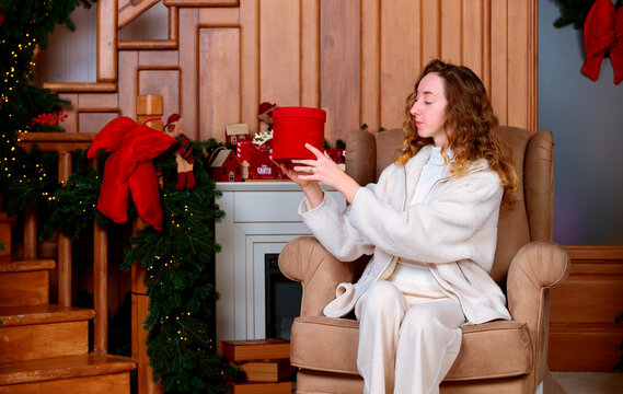 young woman in armchair holding red gift box festive Christmas decorations winter holidays festive season time