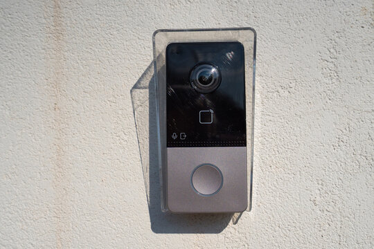 Intercom with call button and camera hanging on white street wall