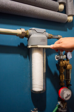 Replacement of the filter on the water supply pipe. A clean filter is installed in a transparent flask and tightened with a wrench