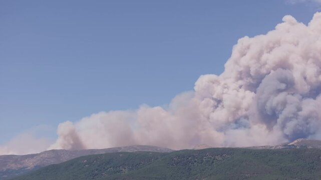 Telephoto drone footage at 167mm capturing the early development of a pyrocumulus cloud above the mountains of the Ti&eacute;tar Valley, generated by intense wildfire activity.