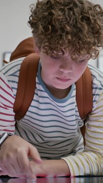 Vertical video of Caucasian boy with backpack using interactive digital display at museum exhibition. Footage is perfect for educational technology and modern museum marketing campaigns
