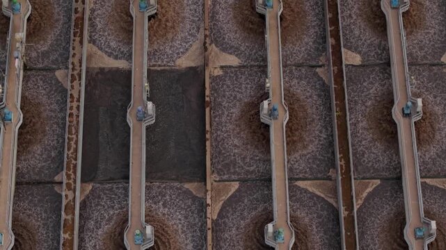 Top down aerial view of sewage treatment plant aeration tanks spraying wastewater in circular clarifiers UK