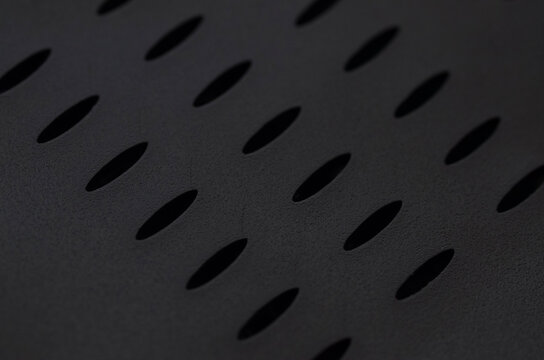 Black Perforated Metal Surface with Repeating Ventilation Hole Pattern
