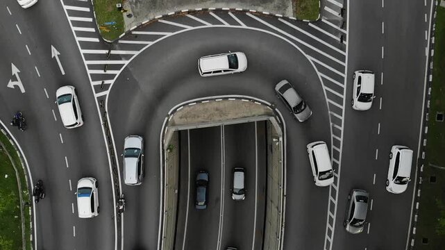 Aerial slow motion footage of vehicles navigating a curved urban road interchange with multiple traffic lanes.