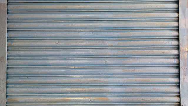Old faded blue metal roller shutter background with horizontal lines provides industrial texture.