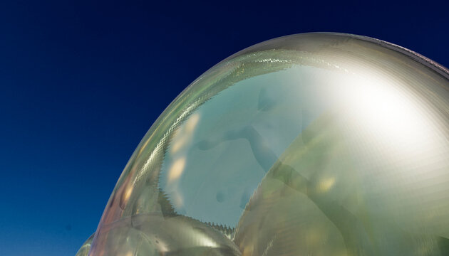 Glass sculpture reflecting distorted figure on curved shiny surface