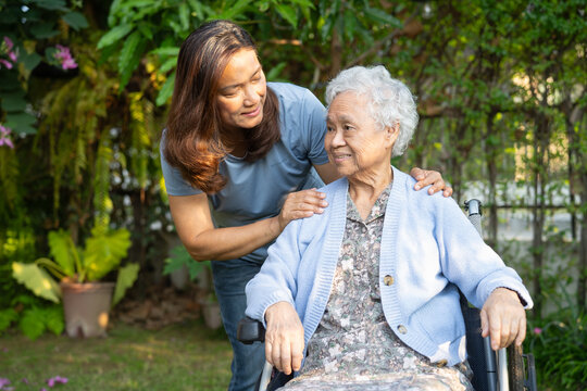 Asian elderly woman disability patient sitting on wheelchair in park.