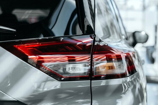 Stylish rear LED lighting of a new car against a bright dealership background.