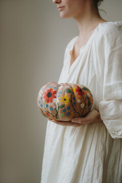 Woman In Oversized White Dress Holding Painted Decorative Pumpkin