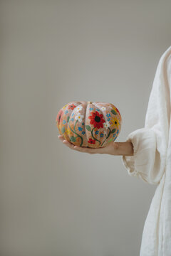 Woman In Minimalist White Linen Outfit Holding Hand Painted Floral Autumn Pumpkin