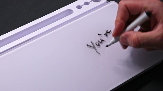 European male hand writing you&acute;re welcome on whiteboard with black pen and erases it with white sponge afterwards for seamless looping message writing on whiteboard. Positive feedback on support.