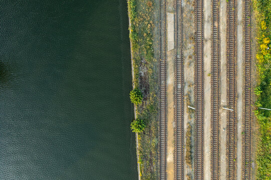 Aerial view of the Container Terminal METRANS featuring parallel railway tracks running alongside a calm river in Wildau, Brandenburg, Germany.