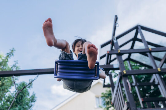 Happy boy laughing while playing on a swing outdoors