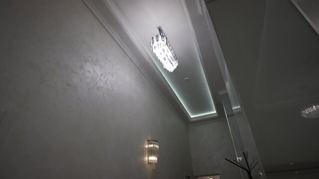 Upward view of hallway ceiling with illuminated crystal chandelier and recessed LED cove lighting emphasizing tray ceiling depth and moulding, with chandelier, ceiling, lighting, led detail