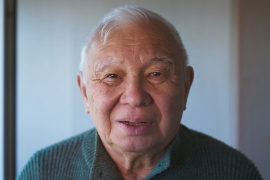 A serene senior man looks at the camera in a close up portrait