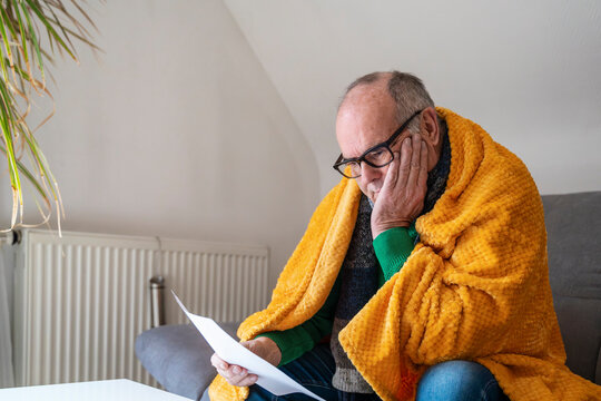 Senior at home under blanket worried about heating and energy bills