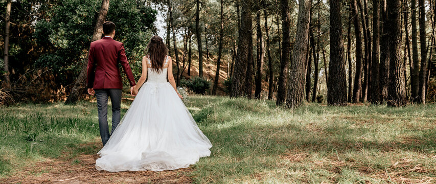 Back view of bride and groom walking in forest