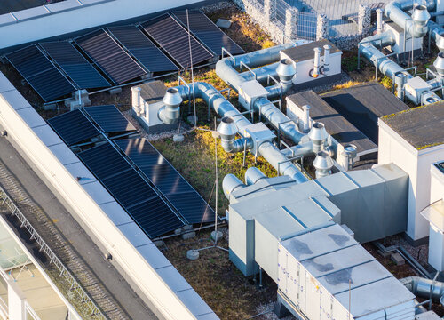Aerial view of solar panels and industrial HVAC ventilation systems on a green rooftop in Gdansk, Pomeranian Voivodeship, Poland.