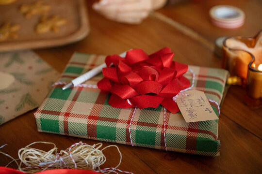 A wrapped Christmas gift decorates a cozy wooden table indoors