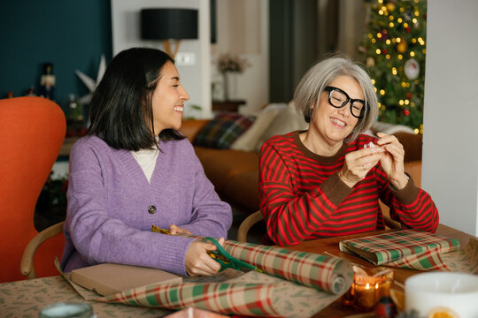 Mother and daughter wrap Christmas presents together at home