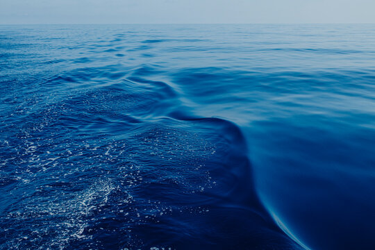 Deep blue sea water creates a wake behind a sailing boat in Ibiza