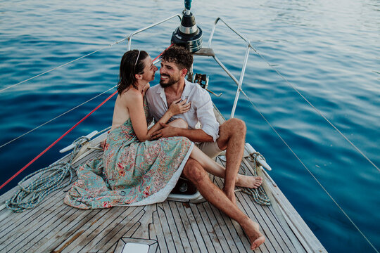 Happy couple sits on a sailboat deck in the Mediterranean sea