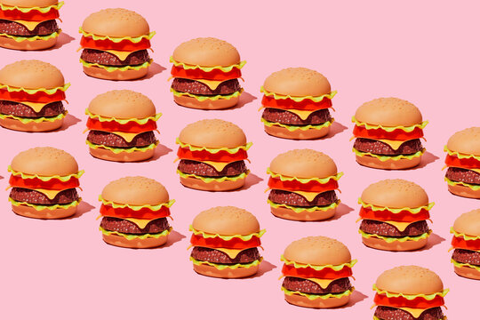 A diagonal pattern of plastic toy hamburgers sits on a pink backdrop