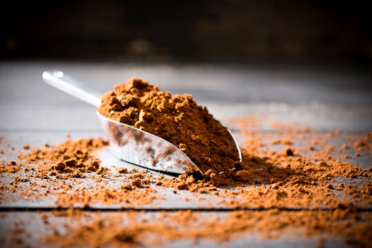 Metal shovel of coffee powder on wood
