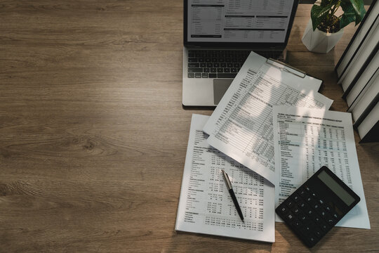 Financial documents, laptop, calculator arranged on office desk for invoice review, receipt accounting, cash flow analysis, bookkeeping, finance reporting with wide copy space.