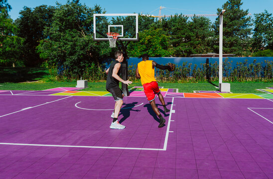 An athlete plays a basketball game on a colorful outdoor court