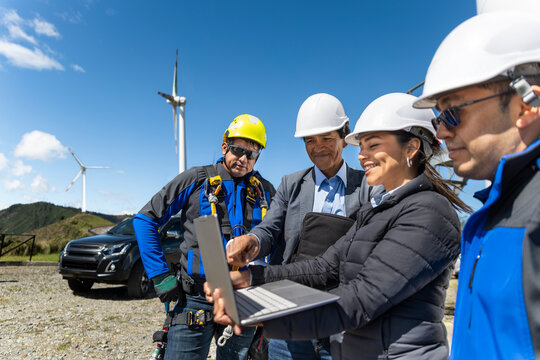 Engineers discuss data on a laptop at a wind farm