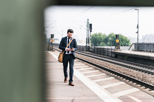 Businessman with cell phone walking at the platform