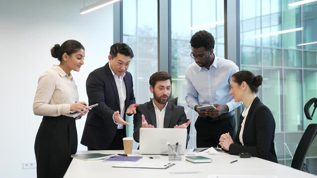 Boss praises group of employees for excellent job at laptop at a workplace in a business office. Happy diverse team professional businesspeople celebrate success and great results, clapping hands