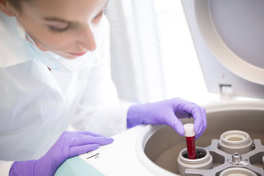 Scientist in lab putting blood sample into centrifuge